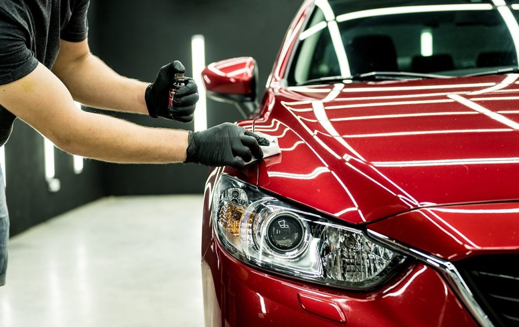 Application of ceramic coating on a red car in a Logan's Auto Detailing & Ceramic Coating shop